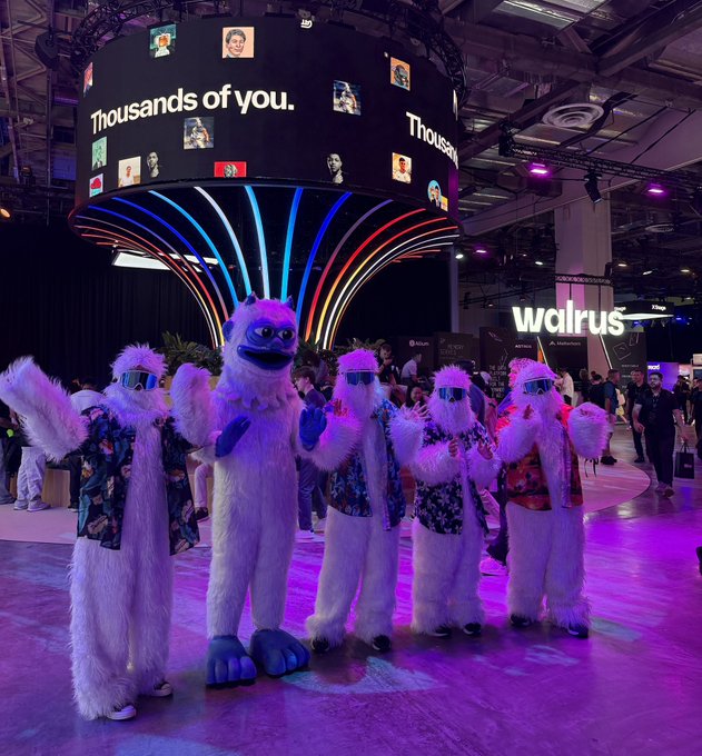 Yeti mascots in colorful sunglasses and Hawaiian shirts pose together at the Sui Network Basecamp booth, where a large overhead screen displays "Thousands of you." surrounded by user avatars, capturing the lively Flurry atmosphere mentioned in the post.