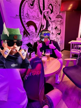 In this image, two individuals, one wearing a traditional Bavarian hat and the other giving a thumbs-up, meet at a bar. The text "RedStone" is clearly visible on a coaster and on a person's leg covering, hinting at a connection to the @redstone_defi project mentioned in the post.