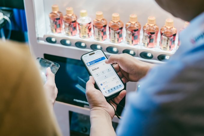 A person uses a smartphone to scan a QR code on a vending machine stocked with pink beverages, with a payment amount of ¥204.43 displayed on the screen, illustrating the seamless stablecoin payment experience the company aims to expand across Japan's retail, dining, and event venues.