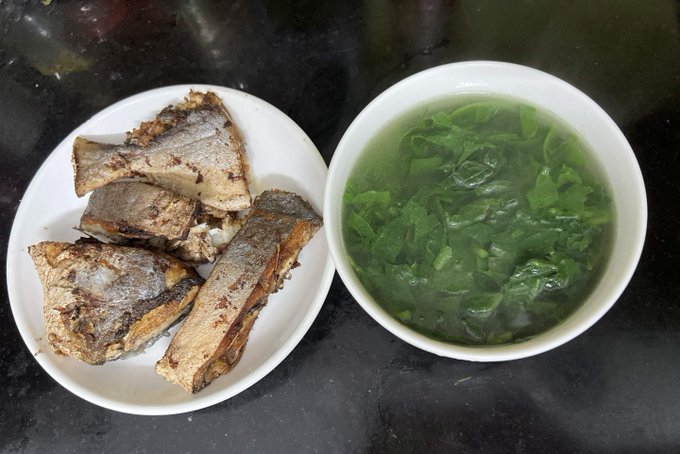 A white plate holds several pieces of crispy pan-fried fish alongside a white bowl filled with a clear green vegetable soup, likely containing leafy greens like mustard or water spinach. The simple, home-cooked meal complements the post's mention of a modest dinner enjoyed after days of gloomy weather, with the fresh greens in the soup adding a vibrant touch to the comforting plate.