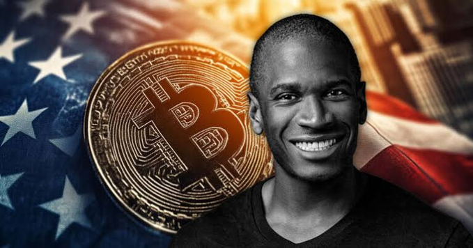 Arthur Hayes smiling in front of an American flag and a large Bitcoin coin.