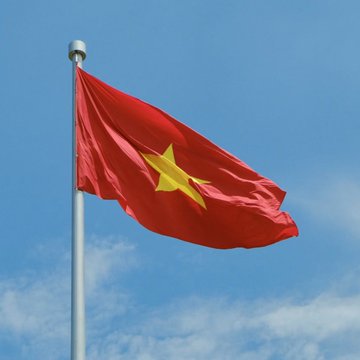 The flag of Vietnam, featuring a yellow star on a red background, waves against a blue sky. The image symbolizes Vietnam, the country referenced in the post discussing its new cryptocurrency market regulations set to take effect on September 1.