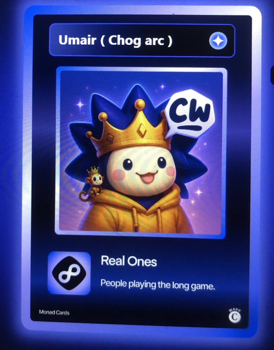 A digital card from 'Monad Cards' featuring a cute cartoon character wearing a gold crown and hoodie with a monkey companion, labeled 'Umair (Chog arc)', 'CW', and 'Real Ones - People playing the long game.'