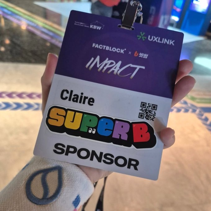 A hand holds a sponsor badge for 'Claire' at a FactBlock × UXLINK Impact event, labeled 'SuperB Sponsor' with a QR code.