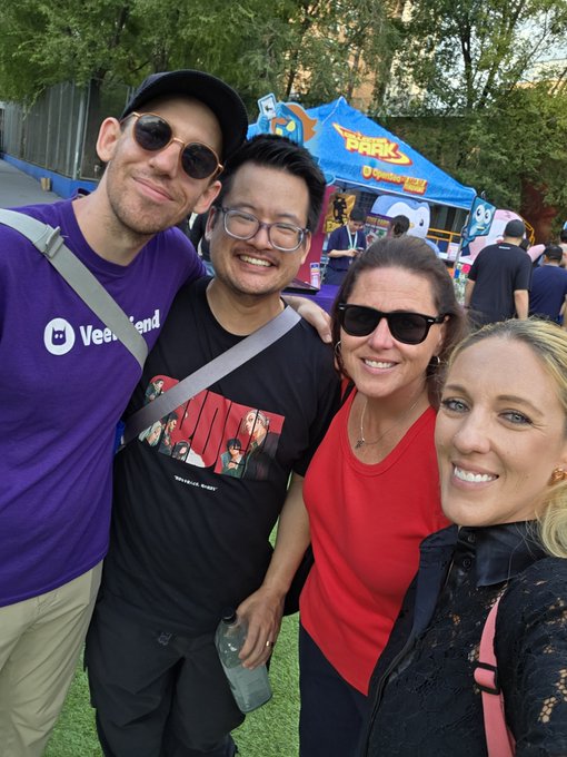 Four people pose for a selfie in front of a 'Bark' themed tent or booth at an outdoor event.