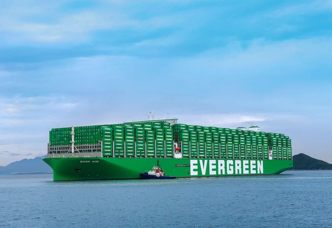 A massive green "EVERGREEN" container ship, the "Ever Ace," is being guided by a tugboat through calm waters under a cloudy sky. The image visually reinforces the post's message about bridging blockchain with established, revenue-generating businesses—like global shipping giants—to drive real-world, long-term adoption of RWA.