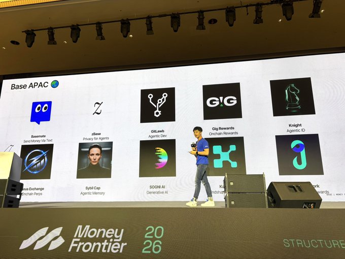 A speaker presents "Base APAC" innovations on stage at Money Frontier 2026, showcasing logos and features of projects including Basemate (Send Money via Text), zBase (Privacy for Agents), GitLawb (Agentic Dev), Gig Rewards (Onchain Rewards), Knight (Agentic ID), Zeus Exchange, Sybil Cap (Agentic Memory), SOGN AI (Generative AI), and Koru.
