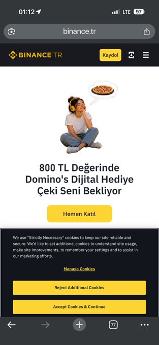 The image shows a smartphone screen displaying a website called "Binance TR düzeldi. İLLA TWIT ATMAMıZ Mı GİRİDILERI." The text on the screen is in Turkish and reads, "Binance TR düzeldi. İLLA TWIT ATMAMız Mı GİRİDILERI". The image also shows a pizza with a woman sitting next to it. The post appears to be about the website or app that is being displayed on the screen, and it seems to be related to the content of the image.