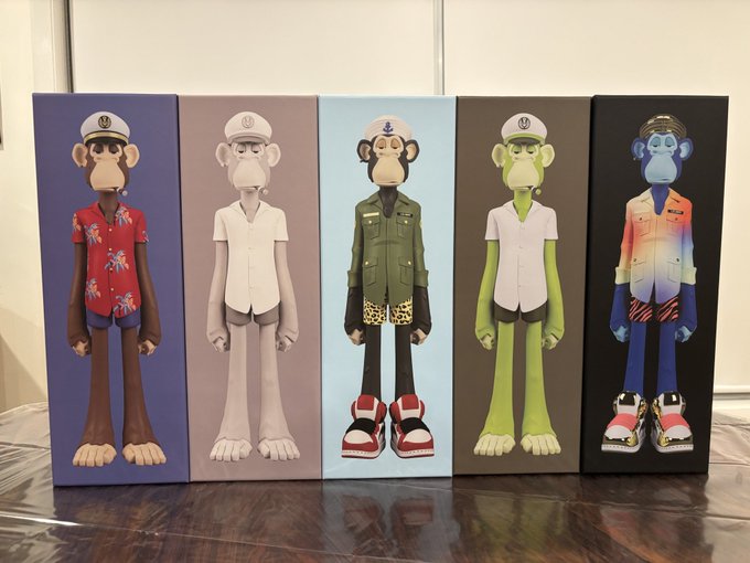 Five colorful designer art toy figures featuring monkey characters in various outfits are displayed in their packaging boxes on a wooden surface.