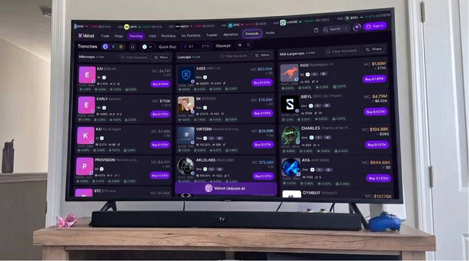 A television screen displays the Velvet Capital DeFi dashboard on w3wet.trade, showing various cryptocurrency trading pairs and market data for tokens including EAI, X402, KIVO, EARLY, SCREEN, SIETY, KAI, VRYTON, CHARLES, PROVISION, MKILGAS, AIVA, BTC, Velvet Unicorn AI, and GYMBOT with prices ranging from $3,910 to $204.88K. The image illustrates the user-facing "AI trading terminal" aspect of Velvet Capital that the accompanying post argues is only a surface-level view of its broader on-chain asset management architecture.