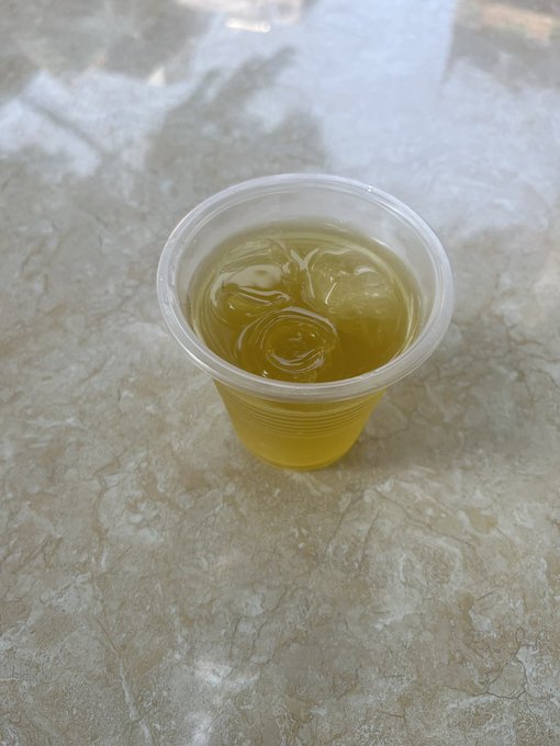 A small clear plastic cup filled with a pale yellow liquid sits on a beige marbled surface. The image metaphorically echoes the post's reflection on market sentiment—a modest cup of uncertainty in an otherwise vast landscape, much as Bitcoin investors are left watching and waiting rather than acting decisively.