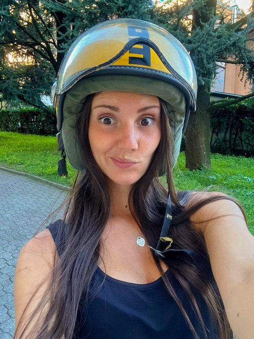 A young woman wearing a green motorcycle helmet and a black tank top takes a selfie outdoors, with the post's reference to "meme szn" fitting her playful, slightly comedic expression as she rides around on a sunny "Green Friday."