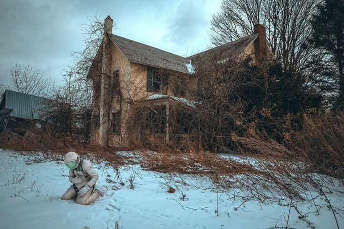 A masked figure kneels in the snow before an abandoned, vine-covered Victorian home under gloomy skies, embodying the haunting isolation and abandoned state suggested by the post's title "No One Is Watching Out For Us." The desolate winter scene and solitary subject reinforce the photograph's self-portrait theme of vulnerability and neglect, shared as a non-fungible token on Transient Labs.