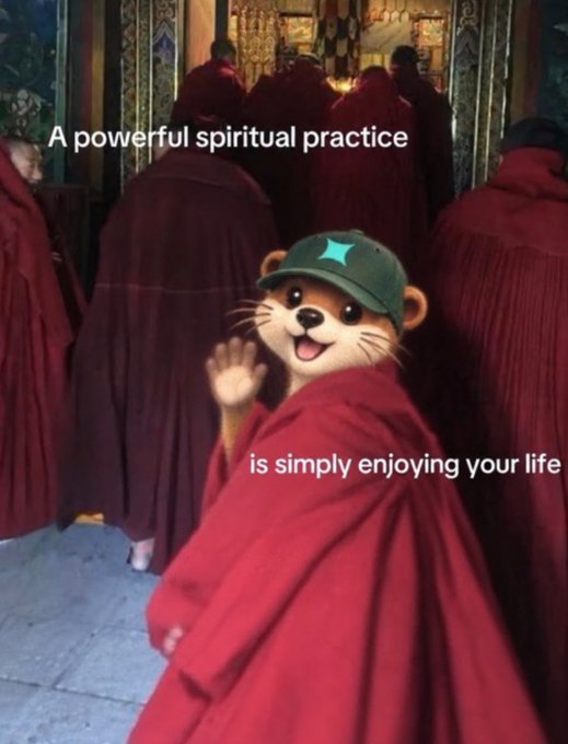 An animated otter character wearing a green cap and red monk robes overlaid on a photo of monks, with the text 'A powerful spiritual practice is simply enjoying your life'.