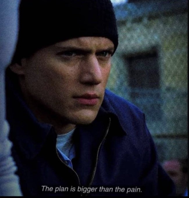 A still image of actor Wentworth Miller as Michael Scofield from the TV show 'Prison Break', wearing a black beanie and dark jacket, with the caption 'The plan is bigger than the pain.'