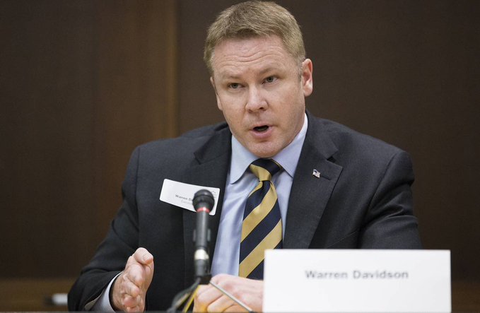 Rep. Warren Davidson speaks at a hearing, with a visible name placard reading "Warren Davidson" in front of him, as he addresses concerns about the CLARITY Act negotiations.