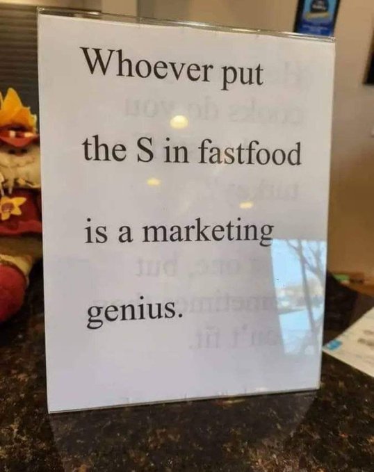 A humorous sign reads "Whoever put the S in fastfood is a marketing genius," poking fun at how "fast food" actually isn't fast. The accompanying "LOL" caption reflects the comedic punchline about the misleading word choice.