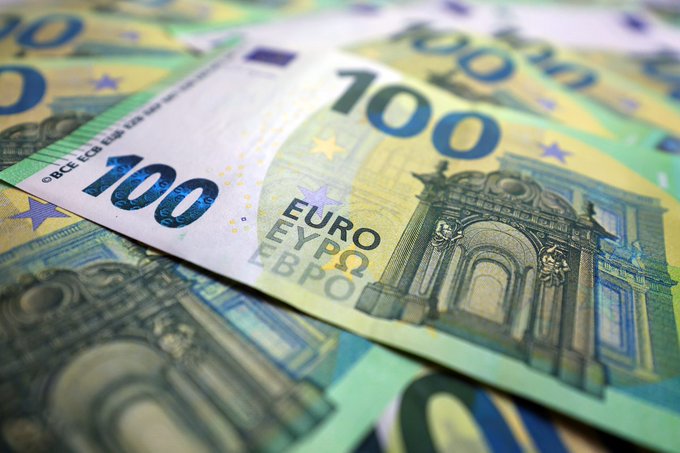 A close-up photograph of multiple 100 Euro banknotes, prominently displaying the "100 EURO" text and classical architectural design, visually representing the EU's currency as the post discusses the European Central Bank's ongoing development and testing of a digital euro with 36 selected payment providers.