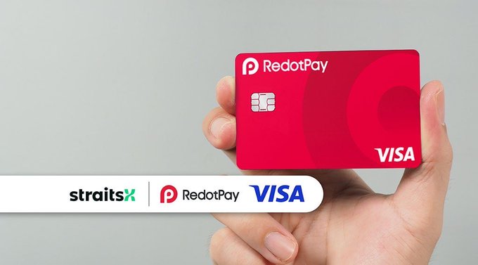 A hand holds a red RedotPay Visa card against a gray background, with a banner below displaying the "straitsX | RedotPay | VISA" logos, visually promoting the free virtual card offer mentioned in the post.