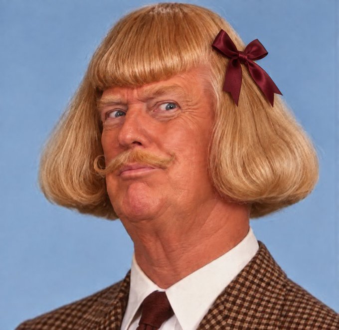 A man with blonde, bowl-cut hair with bangs and a mustache wears a red bow in his hair, dressed in a brown tweed jacket and tie against a blue background.