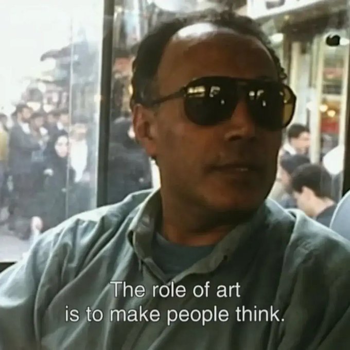 A man wearing dark sunglasses is speaking, with a caption reading, 'The role of art is to make people think.'