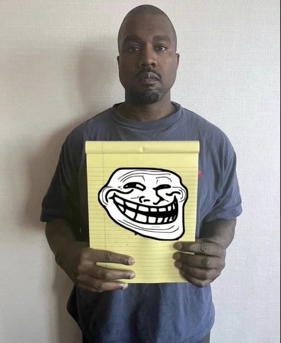 The image features a man holding up a piece of paper with a cartoon face drawn on it, which appears to be a joke or humorous drawing. The caption below the image reads "$TROLL", indicating that this might be a form of humor or a prank.