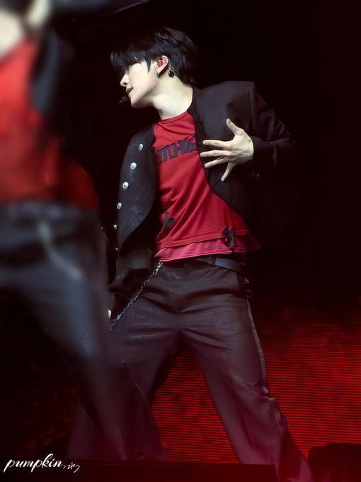 A performer in a black jacket and red shirt with 'TCH' visible is captured mid-performance on a red-lit stage, with a 'pumpkin' watermark in the corner.