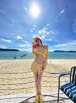 A woman in a yellow-and-white striped two-piece outfit and yellow sneakers poses on a sunny beach, holding a pink drink, with the Binance-themed caption referencing her stylish shoes and praising the photographer for capturing the perfect shot.