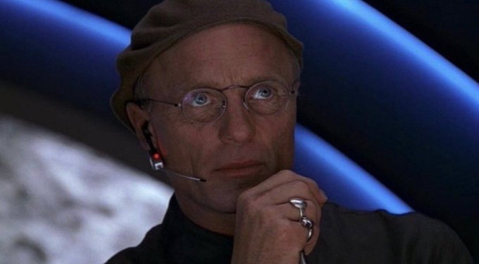 A man with glasses and a headset microphone rests his chin on his hand, looking contemplative and concerned, which complements the post's humorous tone about someone nervously scheming to use confusing terminology to push through a controversial change to a 21 million supply cap.
