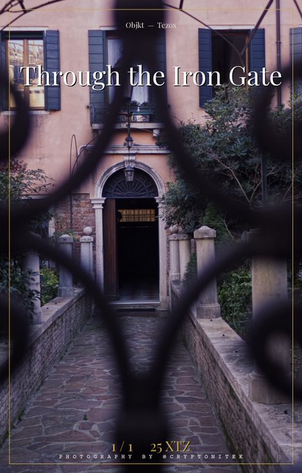 A photograph titled "Through the Iron Gate" showing a cobblestone path leading to a doorway of a peach-colored building, viewed through a dark iron fence. Text reads "Objkt - Tezos", "1/1 25XIX", and "Photography by @cryptonick".