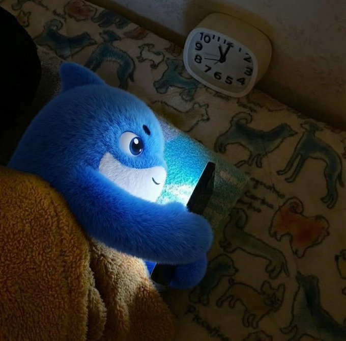 A blue plush Care Bear cuddles under a blanket while illuminated by the glow of a phone screen, with a nearby clock showing nearly 5:00 AM—perfectly capturing the late-night "just one more candle" trading mindset of refusing to log off.