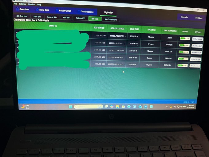A laptop screen displays a DigiDollar Time Lock DGB Vault transaction page, with some areas intentionally redacted in green.