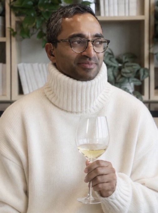 A man in a white turtleneck sweater and glasses holds a glass of white wine, appearing poised and sophisticated with a slight smile. The image humorously contrasts Bitcoin Twitter's excitement over learning "entropy" with this calm, refined demeanor—suggesting their enthusiasm is misplaced or overblown compared to the gentle sophistication on display.
