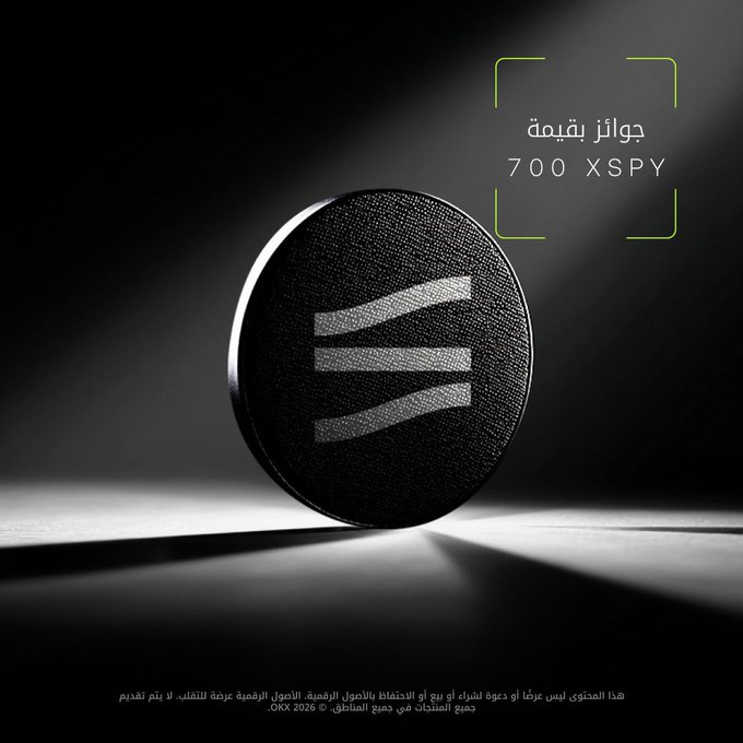 A sleek, dark promotional image features a circular textured emblem with a stylized "M" logo illuminated by dramatic lighting, accompanied by Arabic text reading "جوائز بقيمة 700 XSPY" (Prize pool worth 700 XSPY) and a disclaimer noting the promotion is not available in certain regions, advertising the OKX tokenized stocks trading campaign.