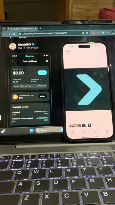 A photograph of a laptop screen showing a YouTube video about WRF ($WTF) token by 'TheMallX' alongside a smartphone displaying a video of the WRF token logo.