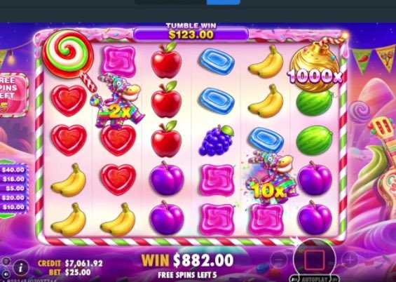 A digital slot machine game screen displays a candy-themed game with a "TUMBLE WIN" of $123.00, a "WIN" of $882.00, a credit balance of $7,061.92, and a bet of $25.00 with 5 free spins left. The grid features various symbols including lollipops, heart candies, apples, bananas, and multiplier values of 2x, 10x, and 1000x, illustrating a successful tumble win being showcased on the Stake platform.