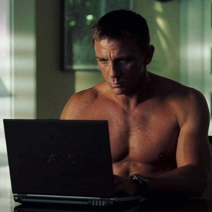 The image shows a shirtless man sitting at a table with an open laptop computer in front of him. The man appears to be working or browsing the internet, possibly for crypto NFTs as suggested by the caption. The image also includes a reference to social media platforms like Twitter and Instagram, which are popular among people who invest in crypto NFTs.