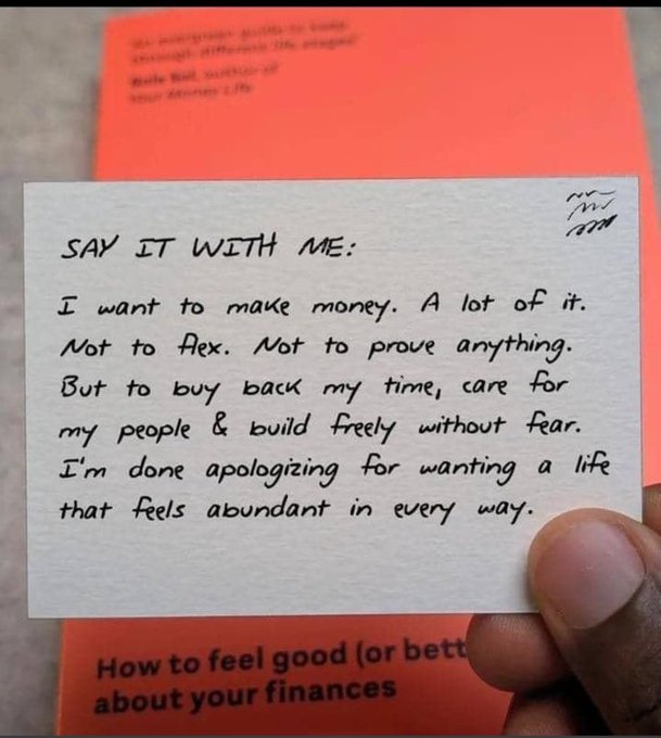 A hand holds a handwritten card titled "SAY IT WITH ME" that reads: "I want to make money. A lot of it. Not to flex. Not to prove anything. But to buy back my time, care for my people & build freely without fear. I'm done apologizing for wanting a life that feels abundant in every way." The card is held over an orange booklet titled "How to feel good (or better) about your finances," symbolizing a mindset shift toward abundance and financial freedom—aligning with the poster's focus on consistent effort, learning, and pursuing $100k in cumulative earnings this year.