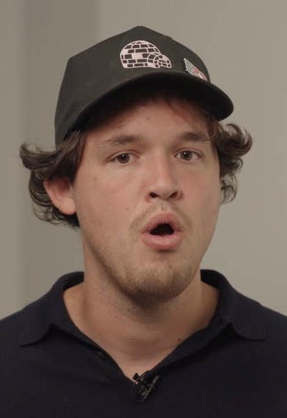 A young man with a goatee wears a black cap featuring a brick-walled igloo logo while speaking during what appears to be an interview, likely referencing his role as Luca Netz of Pudgy Penguins discussing the company's significant Q4 outlook.