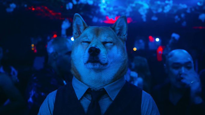 A Shiba Inu dog wearing a vest and tie stands with eyes closed in a dimly lit, blue-toned club scene, embodying the post's reference to "Robinhood dividend hounds" and the playful "dog coin" meme tied to Robinhood ($hood) and crypto investment culture.