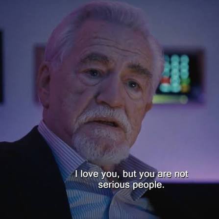 A close-up of an older man with white hair and beard speaking in a dimly lit room, with the subtitle reading 'I love you, but you are not serious people.'