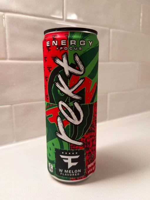 A can of 'ROKT' Energy + Focus drink in watermelon flavor, featuring red and green packaging with a black 'W MELON' label, sitting on a white counter against a tiled backsplash.