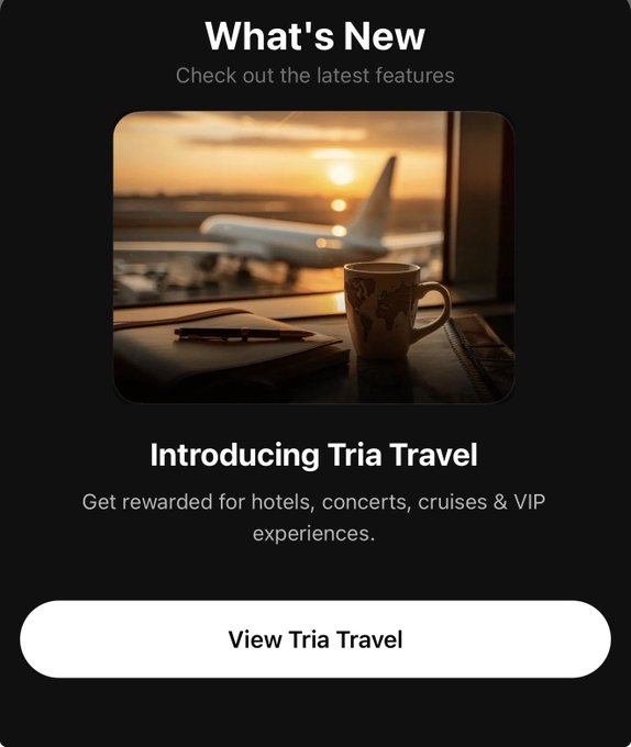 The image shows a travel advertisement for Tria Travel featuring an airplane flying over a sunset with a cup of coffee sitting on top of a table next to it, along with some other items such as a book and a pen. The text on the image reads "What's New? Check out the latest features", which suggests that there is new information or content related to Tria Travel being shared.