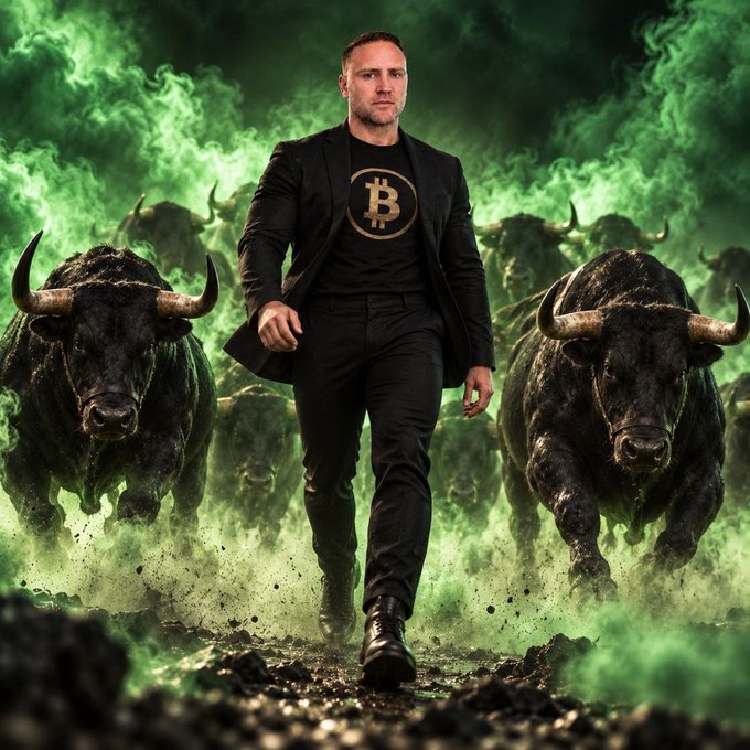A man strides confidently forward wearing a black t-shirt emblazoned with the Bitcoin "₿" symbol, flanked by two charging bulls amid billowing green smoke. The powerful bull imagery reinforces the post's bullish long-term conviction that BTC will reach $1M, dismissing critics as out-of-touch "fossils."