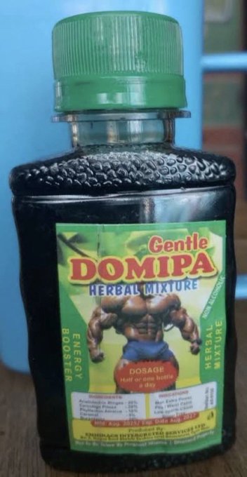 A green bottle labeled "Gentle DOMIPA Herbal Mixture" with an illustrated muscular torso, marketed as an "Energy Booster" with a dosage of "Half or one bottle a day." The "W drink" reference likely refers to "W-Energy," a South African alcoholic energy drink, drawing a humorous parallel between the questionable ingredients of this herbal mixture (which has reportedly been linked to health issues in Nigeria) and the controversial energy beverage.