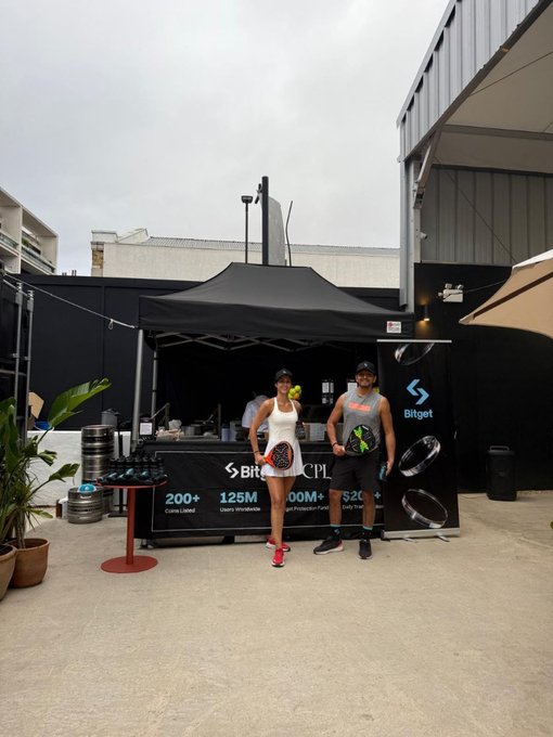 Two athletes pose in front of a Bitget-branded booth at the Crypto Padel League, with signage highlighting "200+ Coins Listed," "125M Users Worldwide," and "100M+ Protection Fund" alongside Flight 3 and CPL branding—visually reinforcing the post's mention of Bitget as official food partner for the finance and crypto padel event.