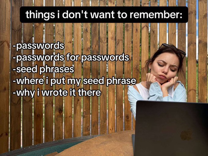 A meme-style image showing a young woman looking bored/frustrated at a laptop with text reading 'things I don't want to remember: -passwords -passwords for passwords -seed phrases -where I put my seed phrase -why I wrote it there'.