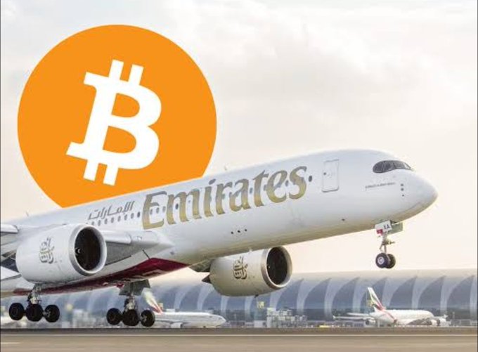 A large Emirates Boeing aircraft is shown taking off from a runway, overlaid with a prominent orange Bitcoin (₿) logo. The image visually reinforces the post's message about Emirates accepting cryptocurrency for flight bookings, symbolizing the real-world adoption of crypto in everyday transactions.