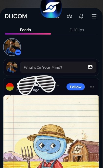 The image shows a cell phone screen displaying a social media app called "Dlicom DC" with a picture of a blue robot wearing a hat, which appears to be a character from a cartoon or storybook. The background of the image is white, making the blue robot stand out. The post on this app encourages users to engage in activities and contribute to the community by liking, sharing, and creating content related to the app's theme. This promotes a sense of togetherness among users who share similar interests and helps build a supportive online environment for the app's growth and success.
