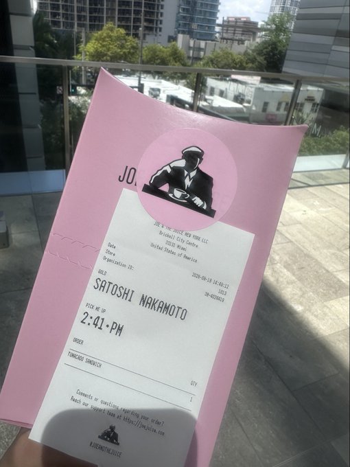 A pink Joe & The Juice receipt displays the order details for "SATOSHI NAKAMOTO," placed at 2:41 PM for a Smoked Salmon Tune toast sandwich, fitting the post's joke about receiving comments on his name across food delivery apps.